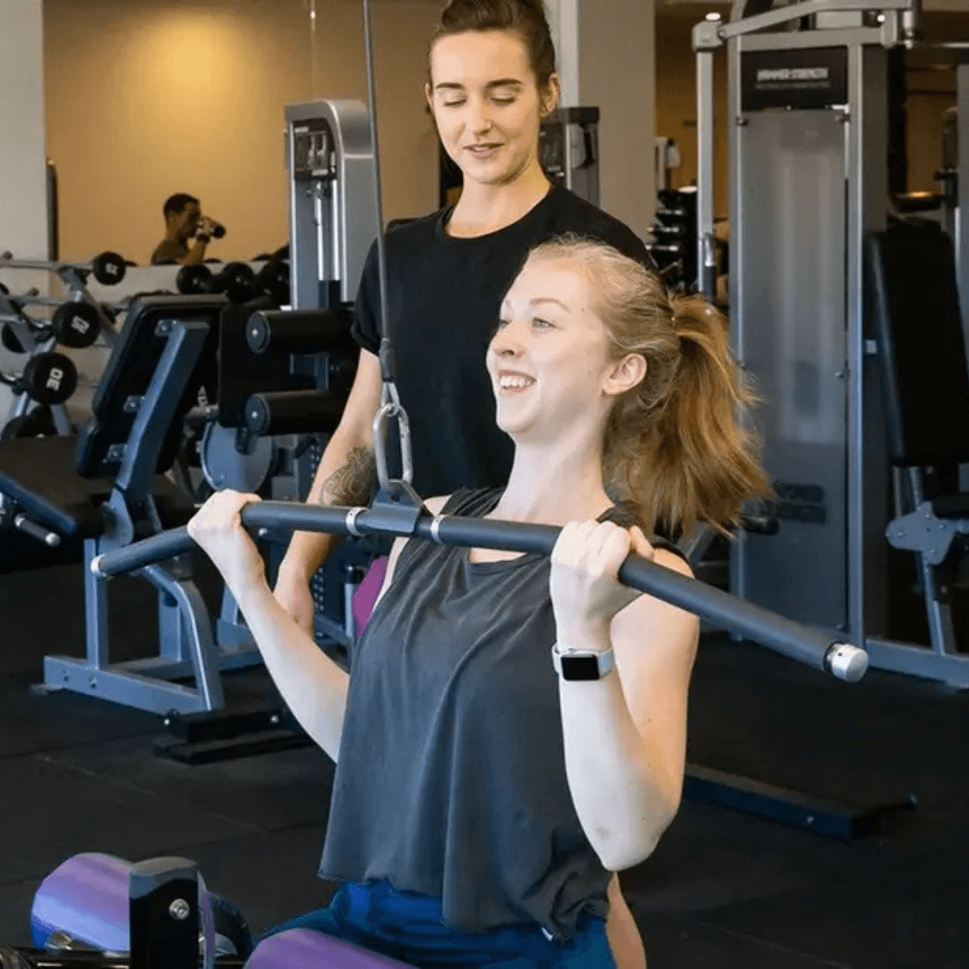 An Exercise Physiologists at InnerFit helping a female member with her recovery from an injury using gym equipment