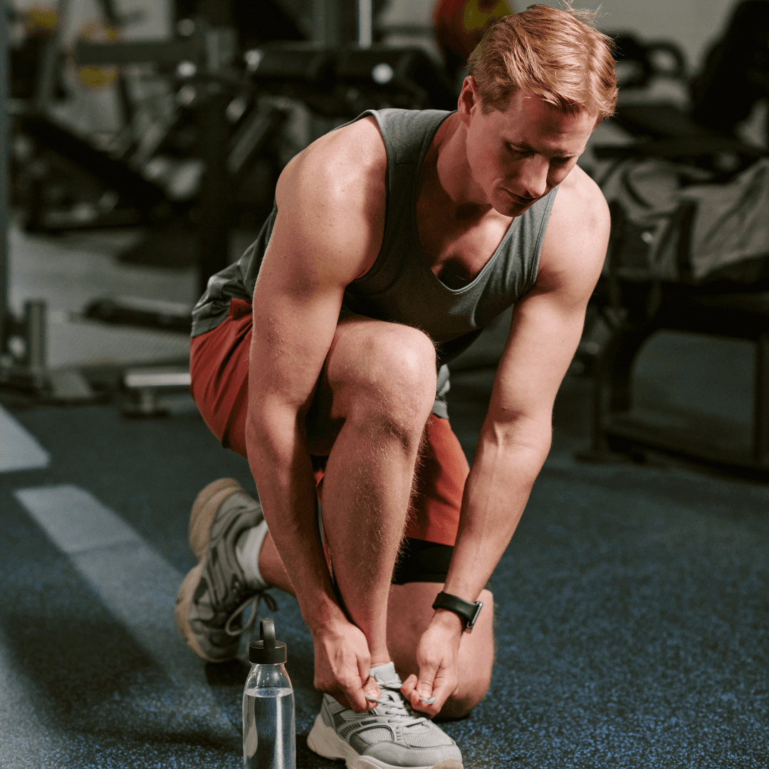A man putting on his sneakers in a gym
