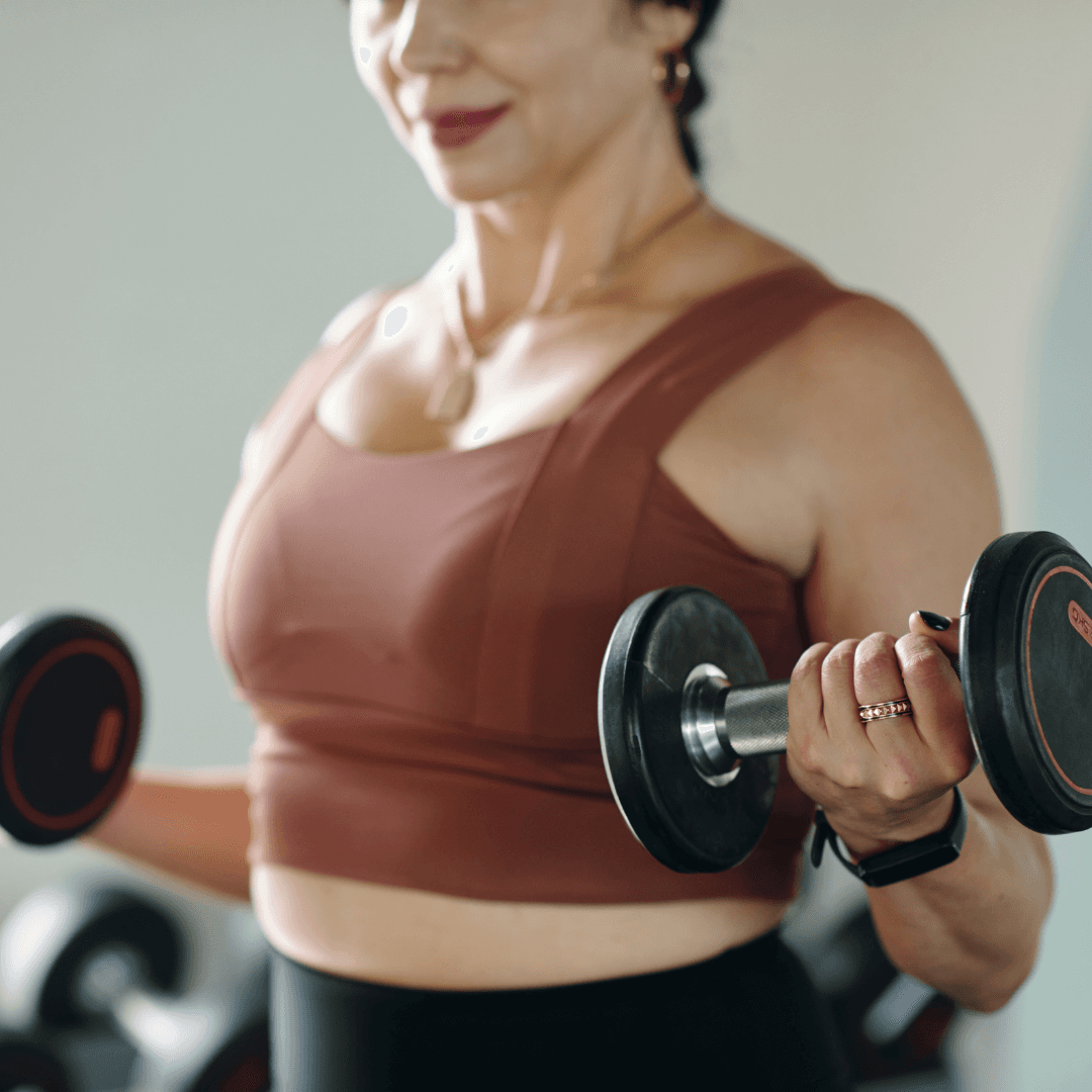 A 50 year old woman using dumbbells in strength training session at InnerFit gym.